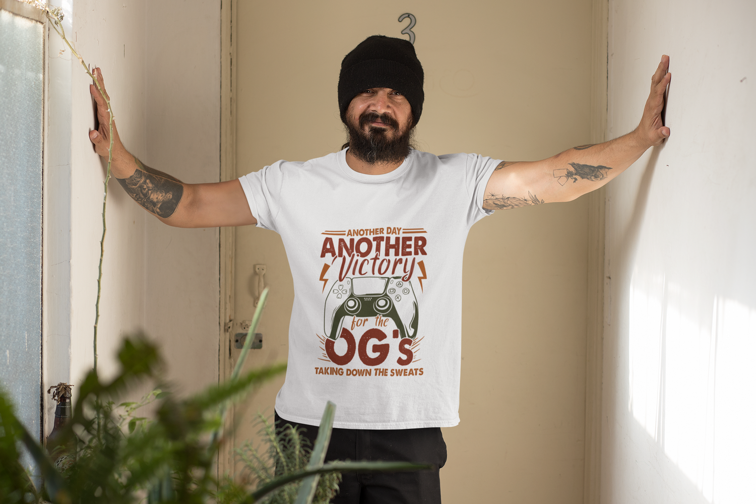 Person wearing a white t-shirt with text and graphics, standing indoors with arms outstretched.