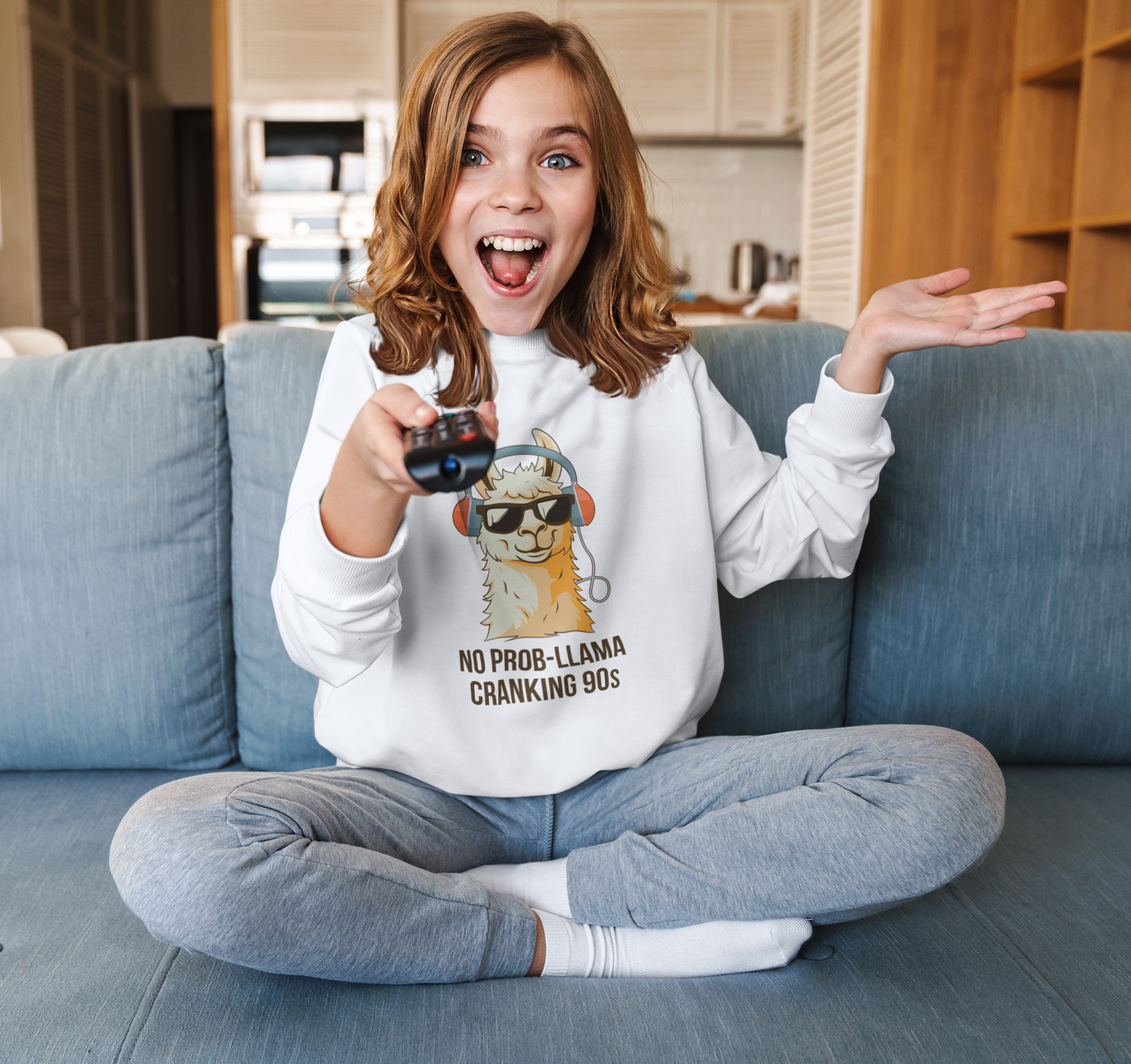 Person wearing a hoodie with a llama graphic and text, sitting on a couch in a living room.